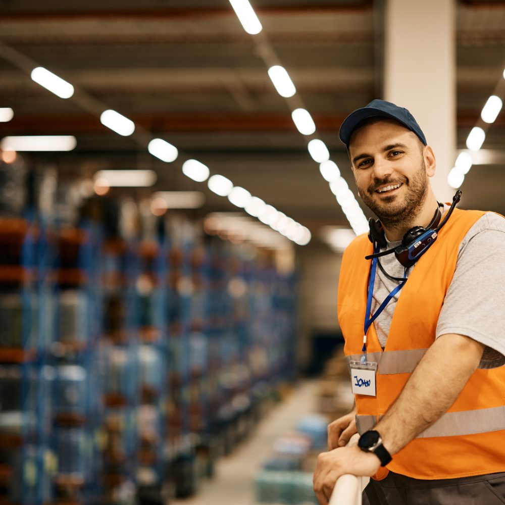 Happy male worker working at distribution warehouse and looking at camera. Copy space.