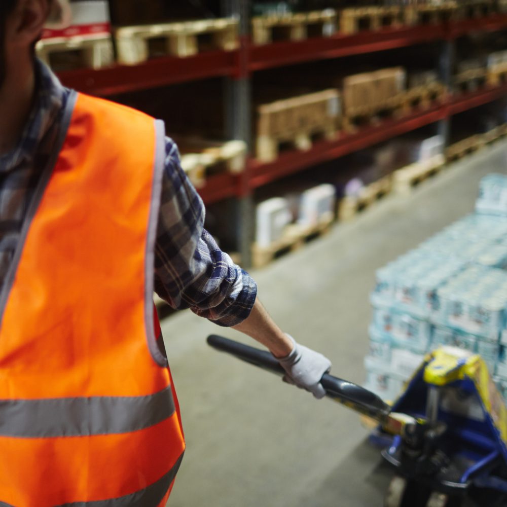 Packed goods on forklift being pulled by worker