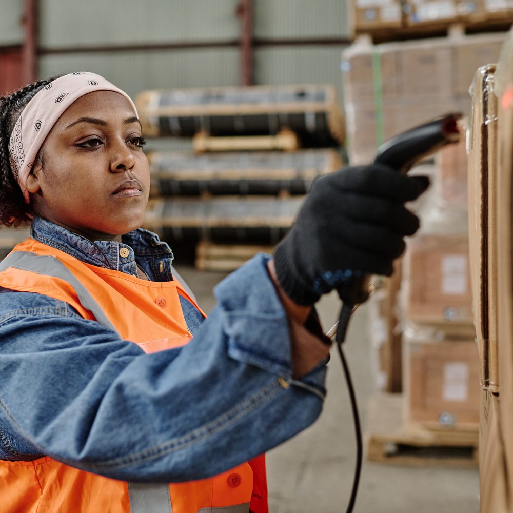 African American worker scanning codes with scanner on box during her work in warehouse